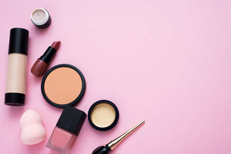 Decorative cosmetics on a pink background. Lipstick, powder, eyeshadow and foundation for bright makeup. Copu spaceの写真素材