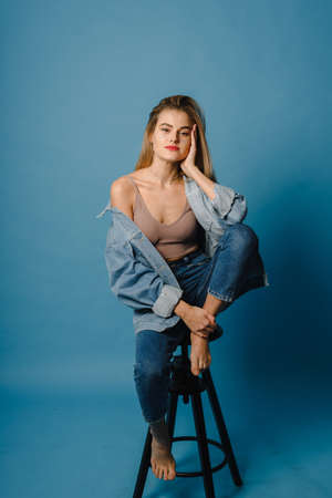 Attractive woman in casual clothes. Fashionable woman-model posing on the chair, studio photographyの写真素材