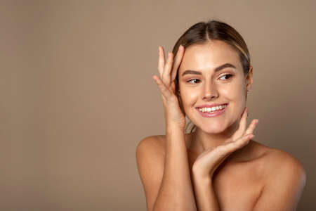 Beautiful young woman smiling after fantastic face treatment. Happy beauty lady excited after spa treatment isolated on background with copy spaceの写真素材