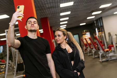 Personal trainings with a trainer. Physical trainer and woman take a selfie in the gymの写真素材