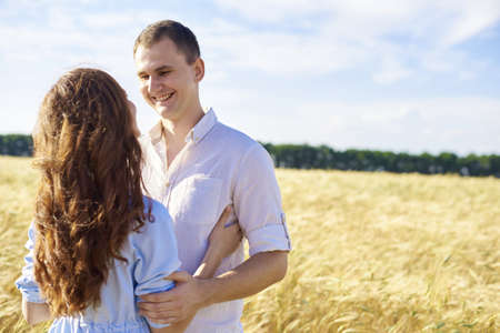 Handsome Caucasian guy wearing white shirt gentle hugs a smiling girl with blond hair in dress.の写真素材