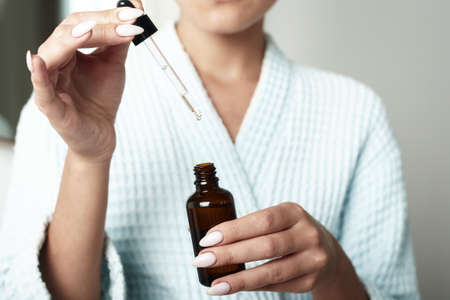 Beautiful Young Woman is Using Moisturizer Anti-Aging Serum Treatment on Her Hands. Beauty Body Skin Care and Cosmetic Apply Conceptの写真素材