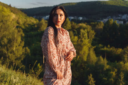 The young woamn is on the hill. The attractive brunette in green. Mysterious woman is looking into the distanceの写真素材