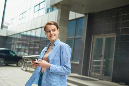 Young female entrepreneur using online banking for transferring money distantly via smartphone. Confident businesswoman texting email letter on cellphone using internetの写真素材