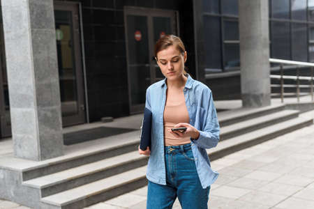 Successful young businesswoman checks email on smartphone during a lunch break outside office. City businesswoman workingの写真素材