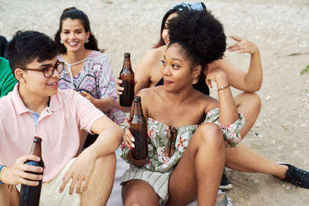 A group of friends are relaxing on the beach and drinking beer. Friendship. Summerの写真素材