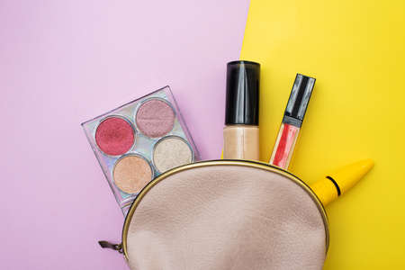 Decorative cosmetic set from a pink cosmetic bag on a pink and yellow background. Copyspace. Makeup artists beauticianの写真素材
