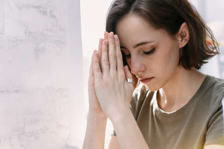 Cute beautiful girl folded her hands in prayer. A woman asks God for helpの写真素材