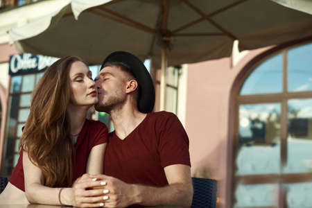 Summer holidays, love and tourism concept. Romantic happy couple kissing in the cafe outdoor in summerの写真素材