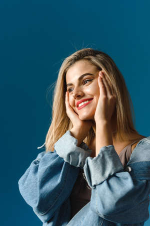 A lovely blonde in a denim jacket gently touches her body. Natural real beauty concept. Trending photoの写真素材