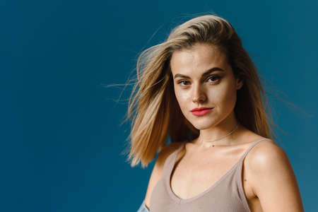 Fashion model with acne in a fashionable oversized blue denim jacket posing near blue wall. Female fashion conceptの写真素材