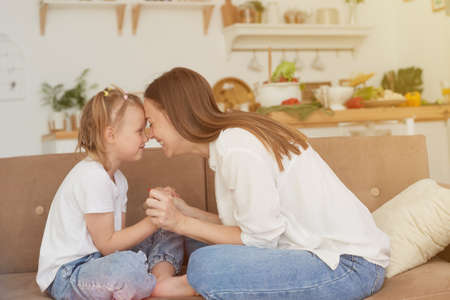 The trusting relationship of mom and daughter. Conversation of a woman with a little girl at home on the couch in the kitchen. Best friends happy motherhood weekend together with kid conceptの写真素材