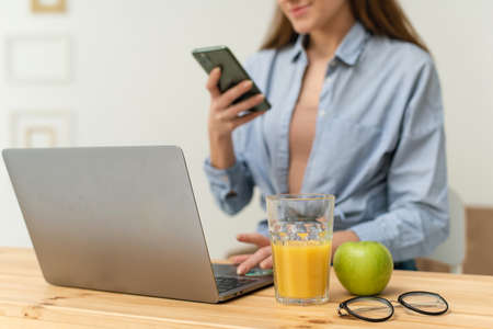 Happy beautiful young woman, sitting at the table at home, taking courses on the Internet and conducting a live broadcast. Work and study from home under quarantine conditionsの写真素材