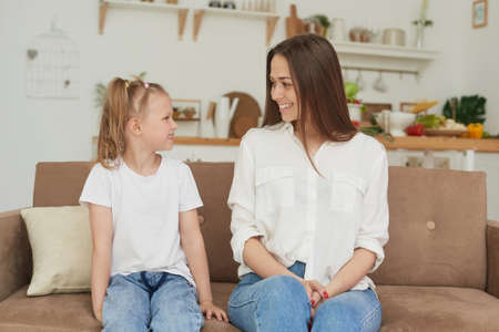 The trusting relationship of mom and daughter. Conversation of a woman with a little girl at home on the couch in the kitchen. Best friends happy motherhood weekend together with kid conceptの写真素材