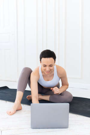 Beautiful adult woman doing sports, stretching and yoga on the mat at home. Quarantined sports during the coronavirus lockdownの写真素材