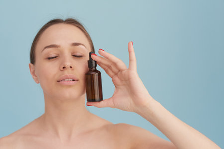 A beautiful young woman moisturizes her skin with a serum. Caring for the skin. Essential Oil For Anti-Aging Therapyの写真素材