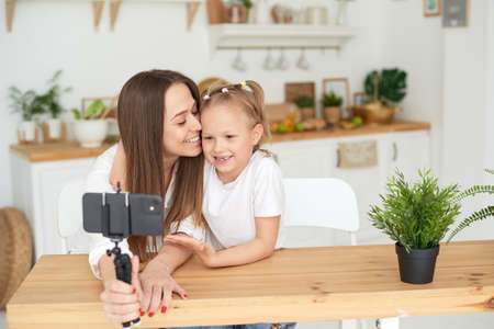 Mom and daughter are having fun and fooling around while recording a video blog. Lifestyle. Spending time with your familyの写真素材