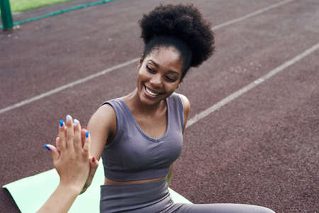 Two different African and Iranian girlfriends give five to each other while exercising. Sports young...