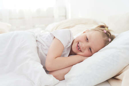 A little girl wakes up in the morning and smiles. Good dreamの写真素材