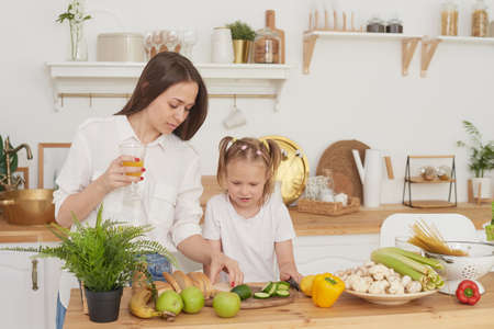 Mom and daughter prepare a salad in the kitchen. Happy loving family are preparing together. The concept of a healthy diet and lifestyle. Family valueの写真素材