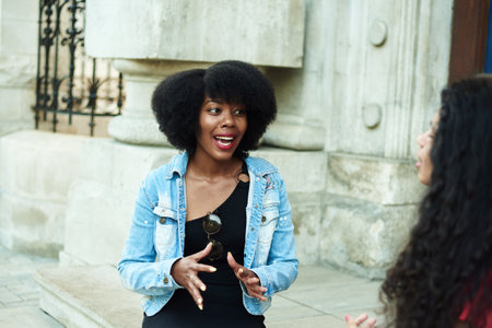 An African American woman emotionally tells a story to her friend. Urban background. Multiethnic groupの写真素材