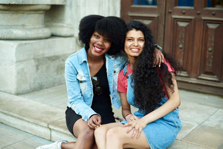 Happy young African American woman smiling, hugging Indian girlfriends and looking at the camera. Multinational friendship conceptの写真素材