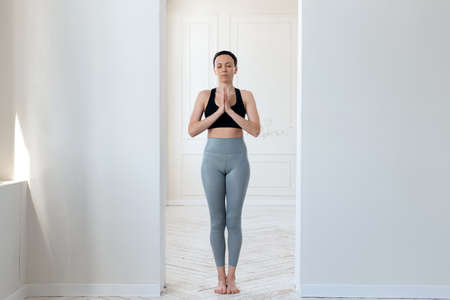 A young woman practices yoga, prays and comprehends Zen in the arch of a bright room. The concept of a healthy lifestyle, meditation and tranquilityの写真素材