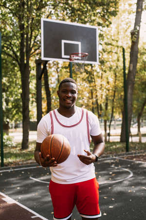 African American basketball player on an outdoor sports ground playing with a ball. doing sports on the streetの写真素材