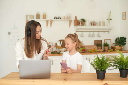 A young mother scolds her daughter for interfering with her work at home. Quarantine. Work remotelyの写真素材