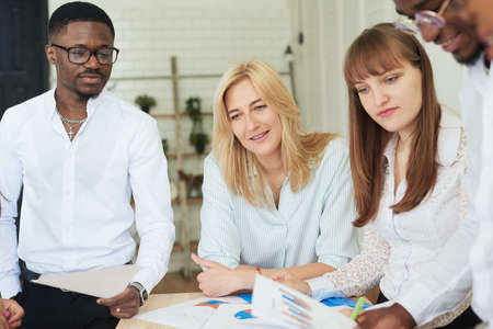 A multinational positive company of people works in the office and looks at work papersの写真素材
