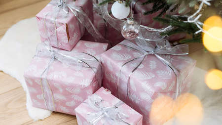 Gifts in pink wrapping under the Christmas tree with a silver ribbon. Christmas and New Year. Web bannerの写真素材