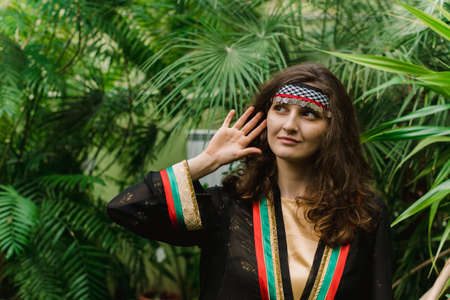 The girl from Jordan on the background of plants and palm leaves. Jordanian girl in the national costume of the Arab stateの写真素材