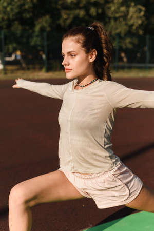 Young woman stretches her arms while playing sports in the stadiumの写真素材