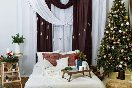 The interior of a modern bedroom is decorated for Christmas. Christmas tree in the apartment.