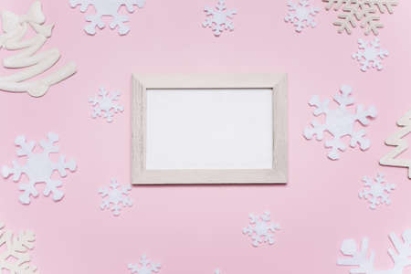 Christmas composition with white decorations on a pink background. Empty white frame with place for text. Christmas pattern. Flat lay, top view, copy space, mock upの写真素材