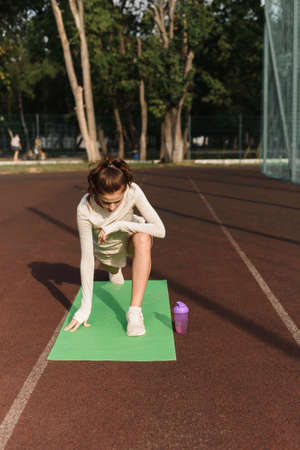 Young beautiful sports model stretches out at the outdoors stadium in the park. A woman goes in for sports and gets in shape.の写真素材