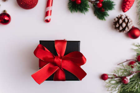Christmas gift with a red bow on a white background with fir branches and decorations on a white background. View from above.の写真素材
