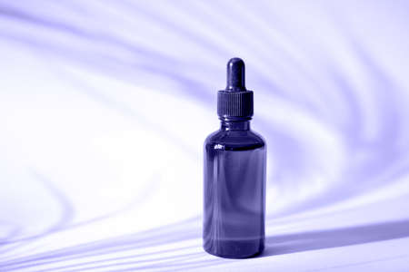 Serum bottle on purple background with palm leaf shadow. Color of the year 2022 Very Peri.の写真素材