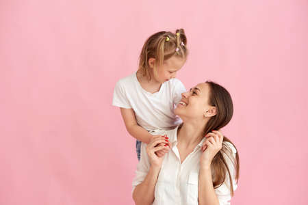 Lovely beautiful young mother and little daughter hug and look at each other. Photo in the studio. Copy space.の写真素材
