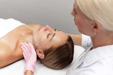 Woman beautician cleans and moisturizes patients skin in spa salonの写真素材