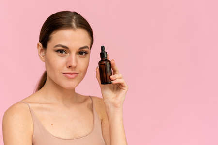 A beautiful young woman moisturizes her skin with a serum. Caring for the skin. Essential Oil For Anti-Aging Therapyの写真素材