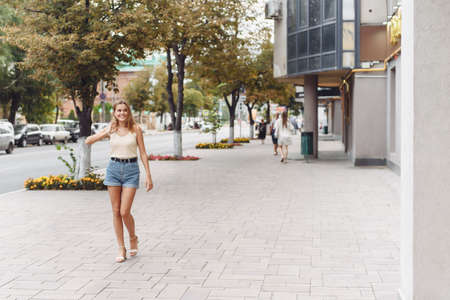 Summer sunny lifestyle fashion portrait of young stylish hipster woman walking on the street, wearing cute trendy outfit, smiling enjoy her weekendsの写真素材