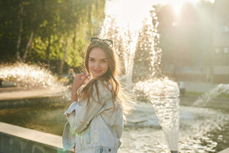 A beautiful girl stands at the solar fountain and smilesの写真素材