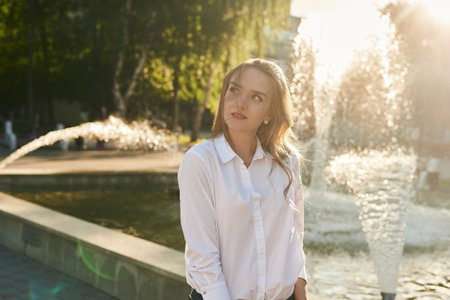 A beautiful girl stands at the solar fountain and smilesの写真素材