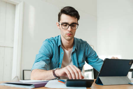 A young man manages finances from home. Economist works at home, freelance.の写真素材