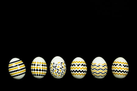 Golden, black, white easter eggs on a black background. Geometric. Minimal concept. Top view. Card with copy space for text.の写真素材