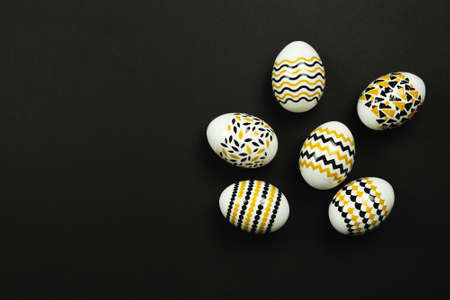 Dark Easter card with copy space for text. Easter golden decorated eggs with stripes and dots - flat lay, copy space.の写真素材