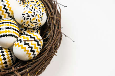 Happy Easter concept. Preparation for the holiday. Easter eggs with patterns of stripes, zigzags, dots in a nest on a white background. Simple minimalism, flat lay, top view, copy spaceの写真素材