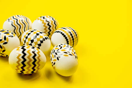Easter decorated eggs in black and yellow stripes and a dot on a yellow background. Minimal Easter concept. Flat lay of trendy easter eggs.の写真素材