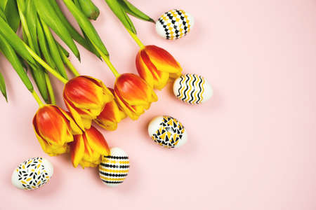 Golden, black and white Easter eggs with a geometric pattern with a tulips flowers on pink background. Copy space.の写真素材